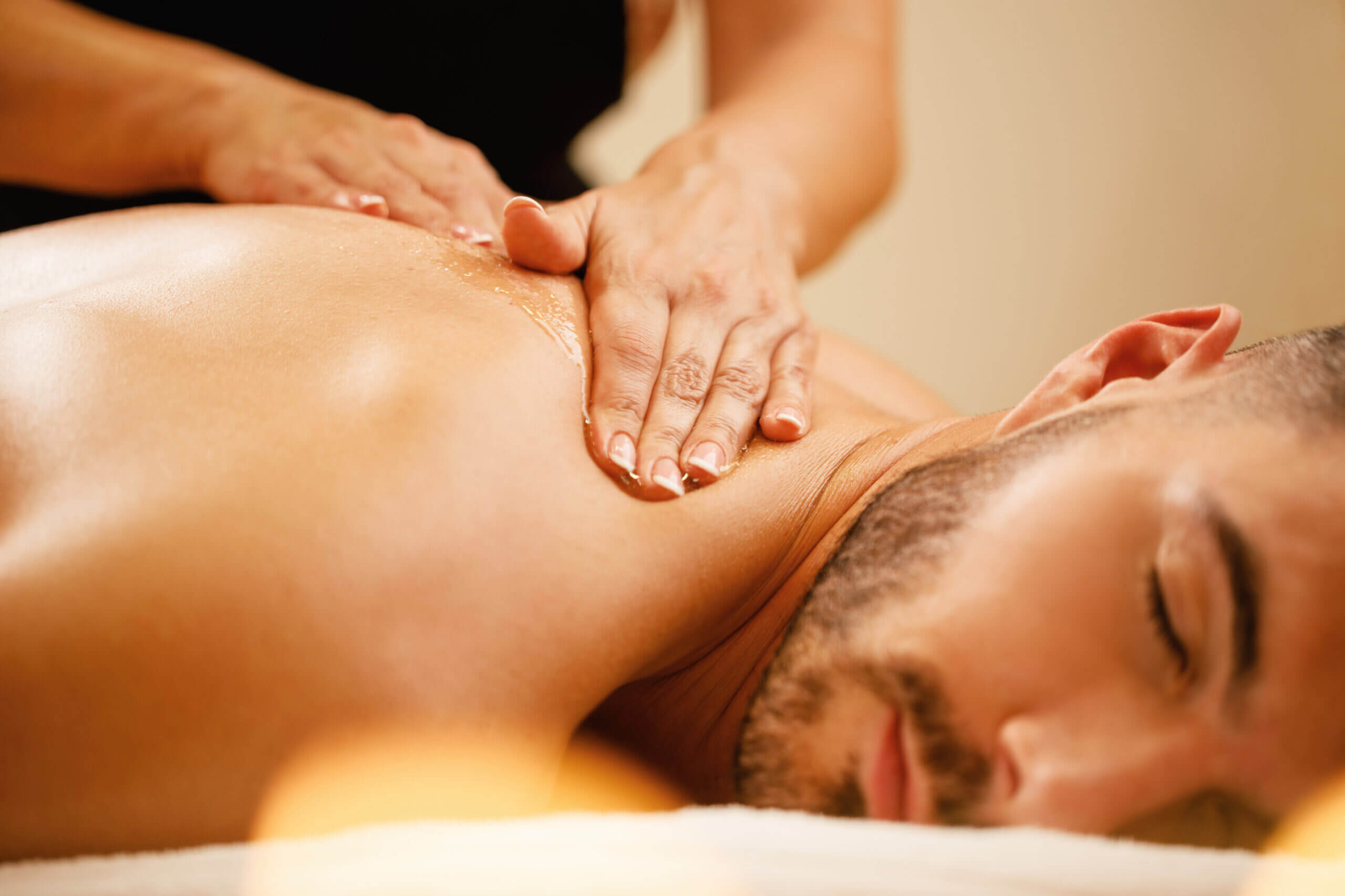 Close-up of man having back massage with honey at health spa. Closeup Man Enjoying Relaxing Back Massage With Honey Spa Scaled 1